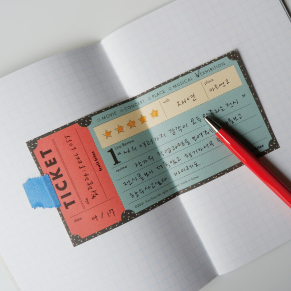 Notebook with a movie ticket-style bookmark and a red pen on a white background