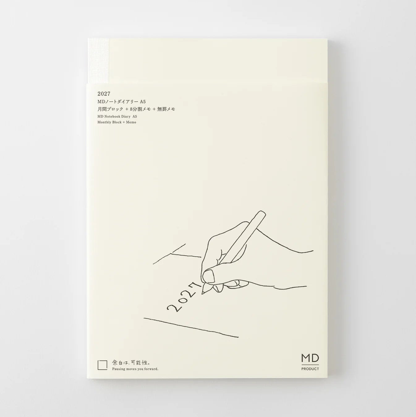 A cream-colored notebook or journal cover with minimalist black line art showing a hand writing '2027' on a pencil. The cover features Japanese text at the top left and a small 'MD' logo at the bottom right, set against a clean light gray background.
